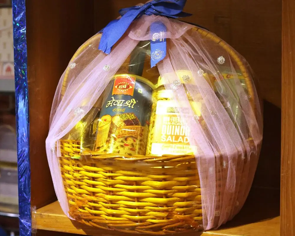 A wicker gift basket packed at Ahuja Proteins, wrapped in pink net and tied with a blue ribbon bow