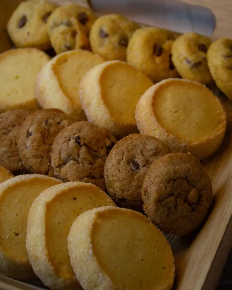 An assortment of butter, oat and chocolate chip biscuits in a wooden tray
