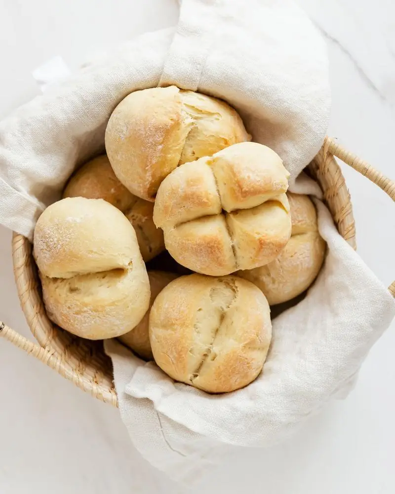 Soft white bread buns in a cloth-lined basket
