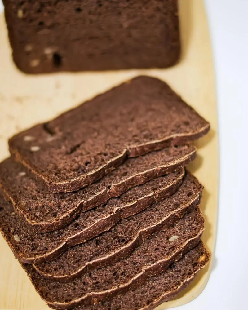 A plain chocolate loaf cake, sliced, on a wooden board