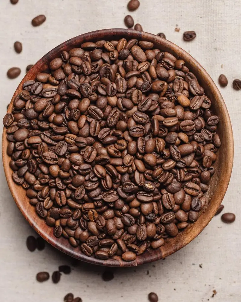Roasted coffee beans in a wooden bowl on linen