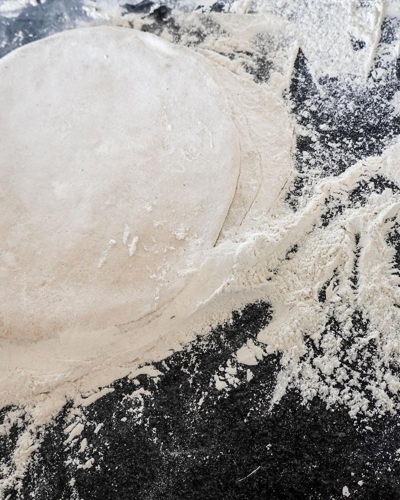 A rolled pizza base on a floured surface