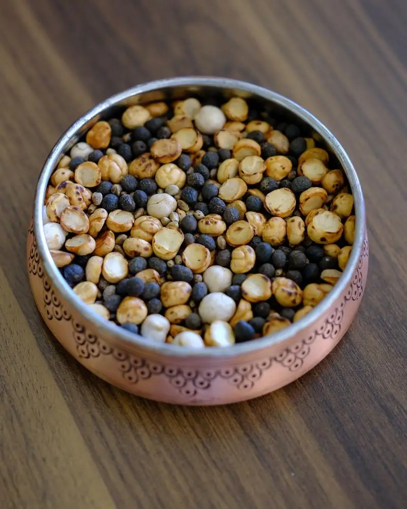 A roasted savoury mix of grams and seeds in a decorated copper bowl