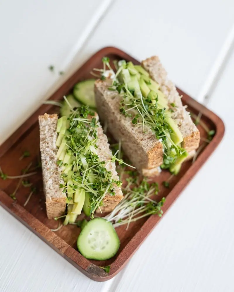 A vegetable sandwich cut into triangles on a wooden board