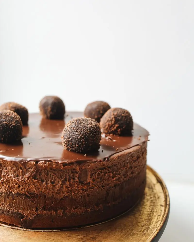 A whole chocolate cake under dark ganache, topped with truffles