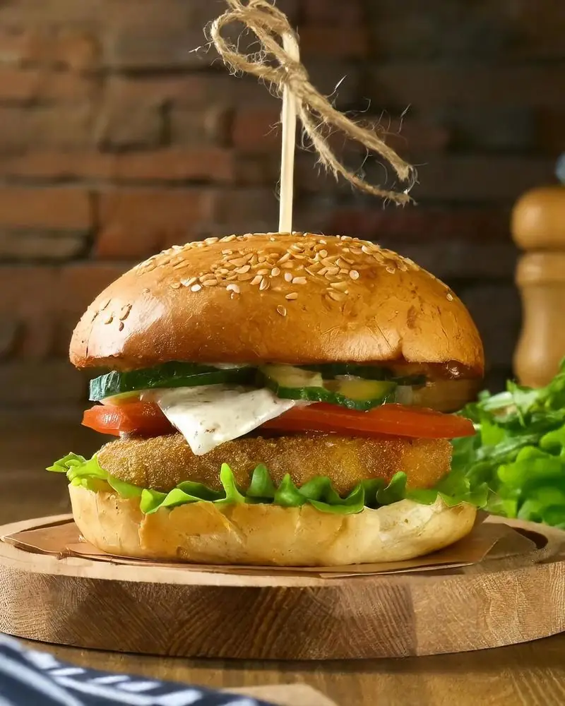 A crumbed vegetable patty burger in a sesame bun with lettuce and tomato